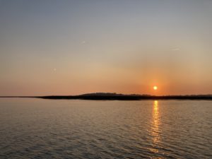 Sunset over land behind a plane of water